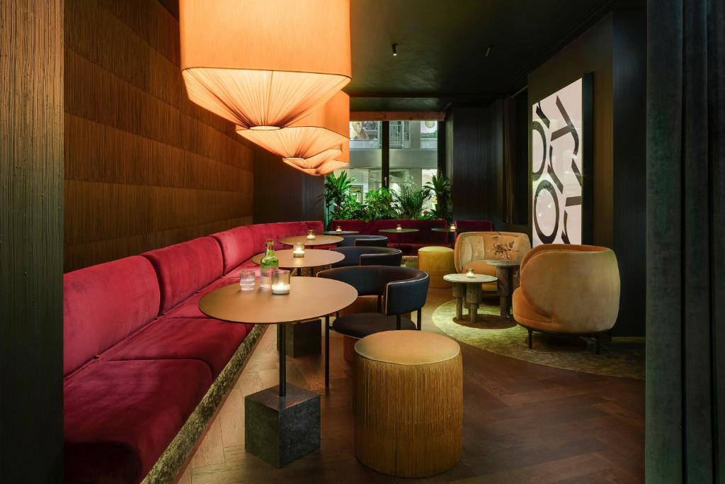 a restaurant with a red couch and tables and chairs at Mandarin Oriental, Munich in Munich