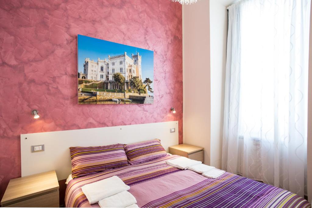 een slaapkamer met een bed en een roze muur bij Rooms Boutique Carducci in Trieste