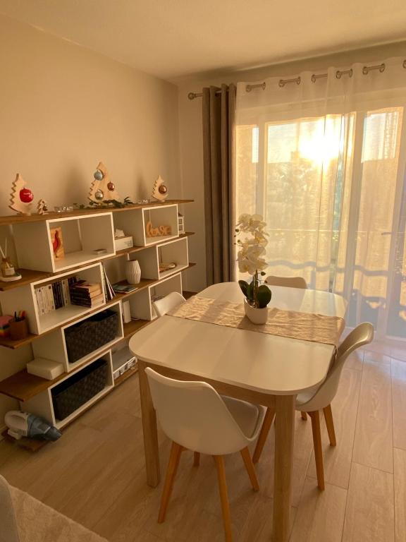 une salle à manger avec une table et des chaises blanches dans l'établissement La Résidence Fleurie, vue sur le Lac Léman, à Thonon-les-Bains