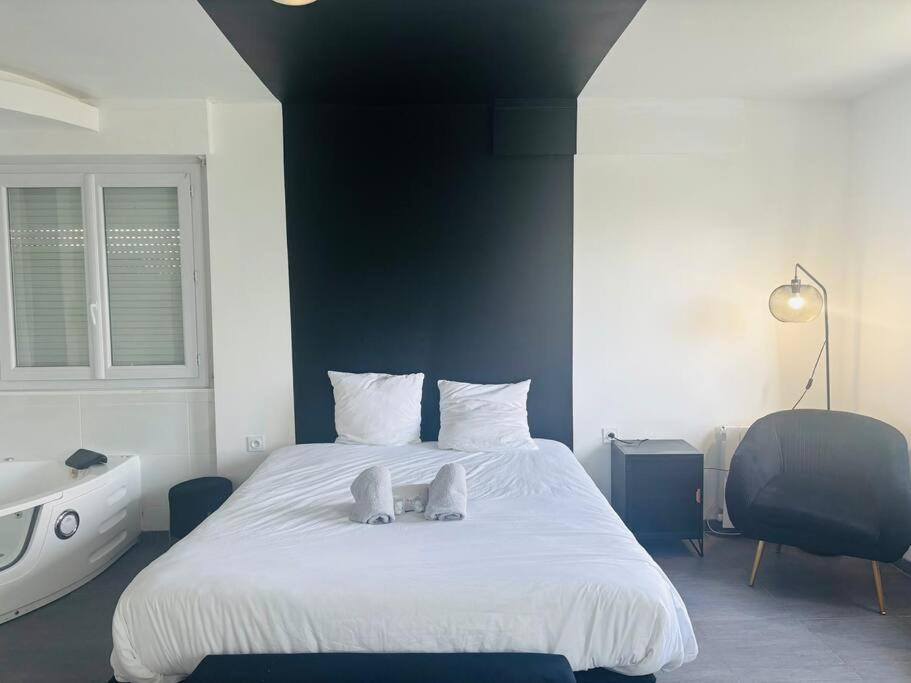 - une chambre avec un grand lit blanc et une baignoire dans l'établissement Charmant Studio 3 avec Jacuzzi à Quéven, à Quéven