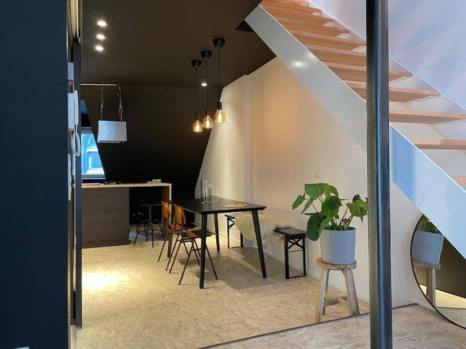 a dining room with a table and chairs and a staircase at Duplex in the historic heart of Liège - 3rd floor in Liège