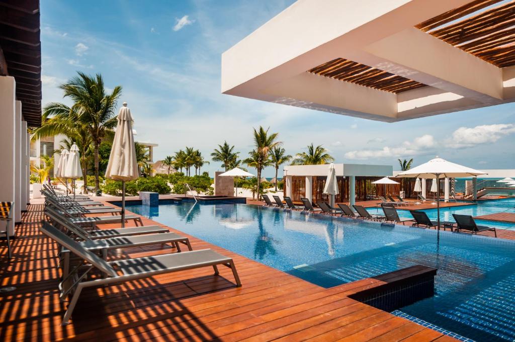 einen Pool in einem Resort mit Liegestühlen und Sonnenschirmen in der Unterkunft Ph en resort de lujo con acceso a la playa y todas las amenidades in Cancún