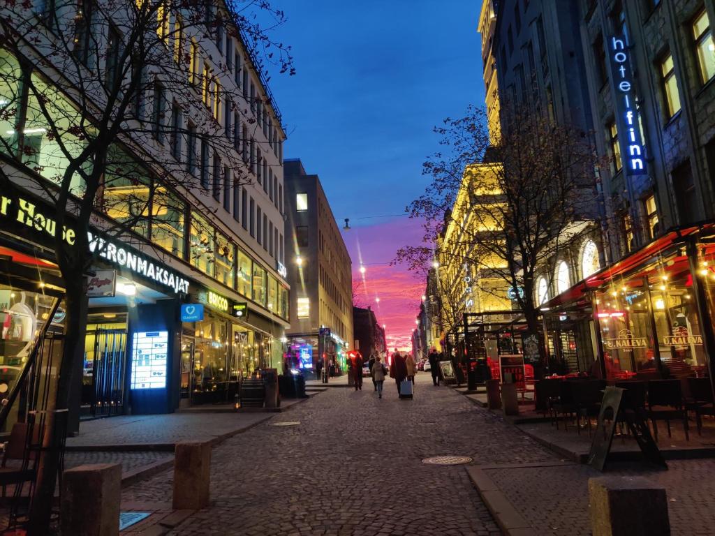 une rue de la ville la nuit avec des gens qui marchent dans la rue dans l'établissement 2StepsFromHelsinkiRailwayStation, à Helsinki