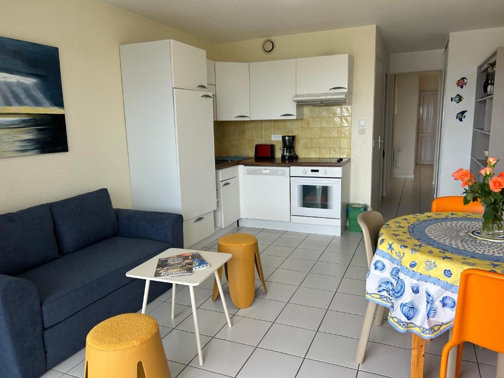 un salon avec un canapé et une table et une cuisine dans l'établissement appartement en front de mer, à Guidel
