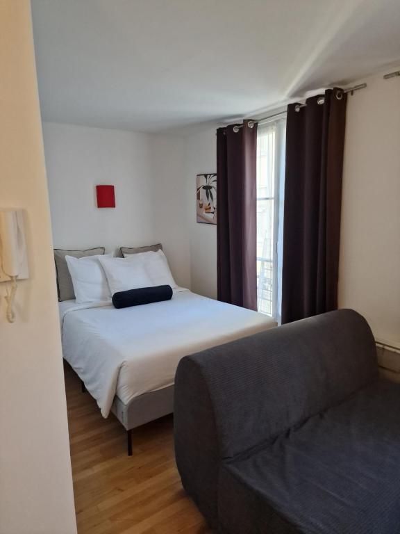 une chambre avec un lit, un canapé et une fenêtre dans l'établissement belle appartement au canal de saint martin, à Paris