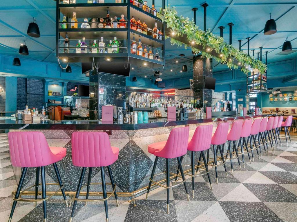 a row of pink stools in front of a bar at Hotel Belmont Vancouver - MGallery Collection in Vancouver