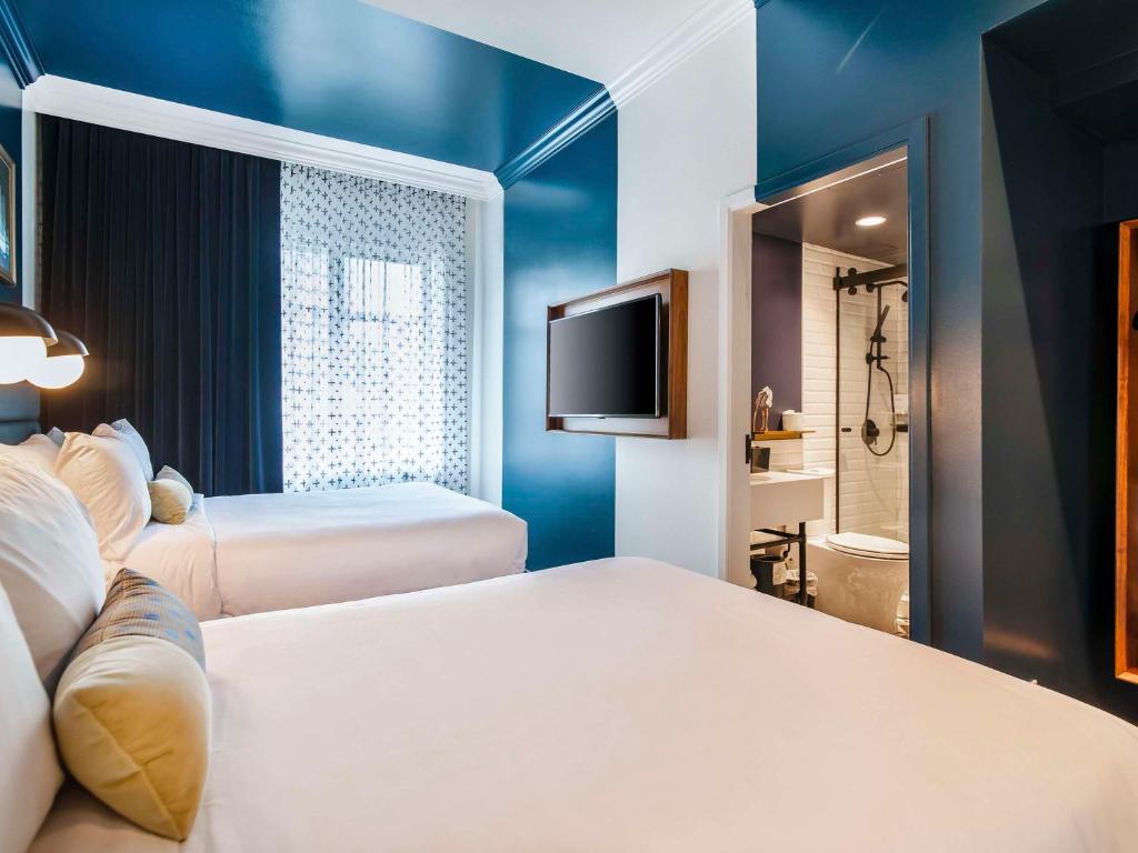 a hotel room with two beds and a flat screen tv at Hotel Belmont Vancouver - MGallery Collection in Vancouver