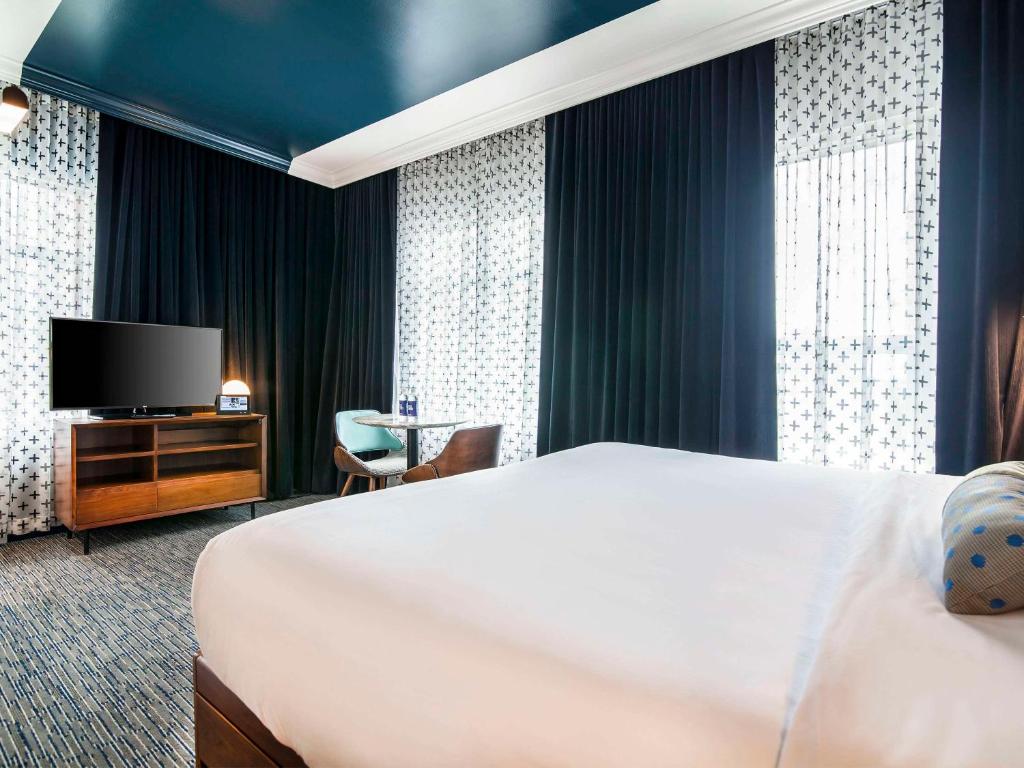 a hotel room with a bed and a flat screen tv at Hotel Belmont Vancouver - MGallery Collection in Vancouver