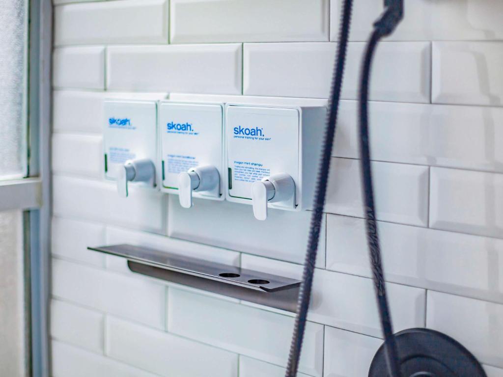 a soap dispenser on a wall in a bathroom at Hotel Belmont Vancouver - MGallery Collection in Vancouver