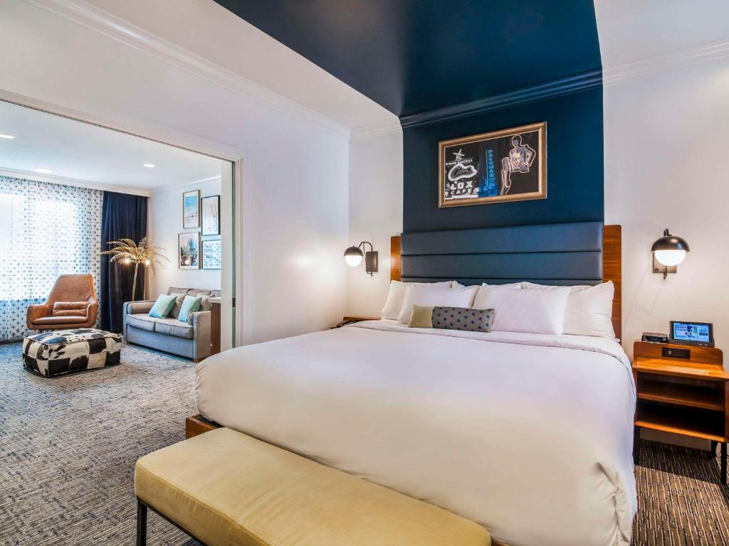 a bedroom with a large bed and a living room at Hotel Belmont Vancouver - MGallery Collection in Vancouver