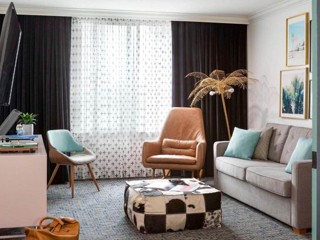 a living room with a couch and a chair at Hotel Belmont Vancouver - MGallery Collection in Vancouver