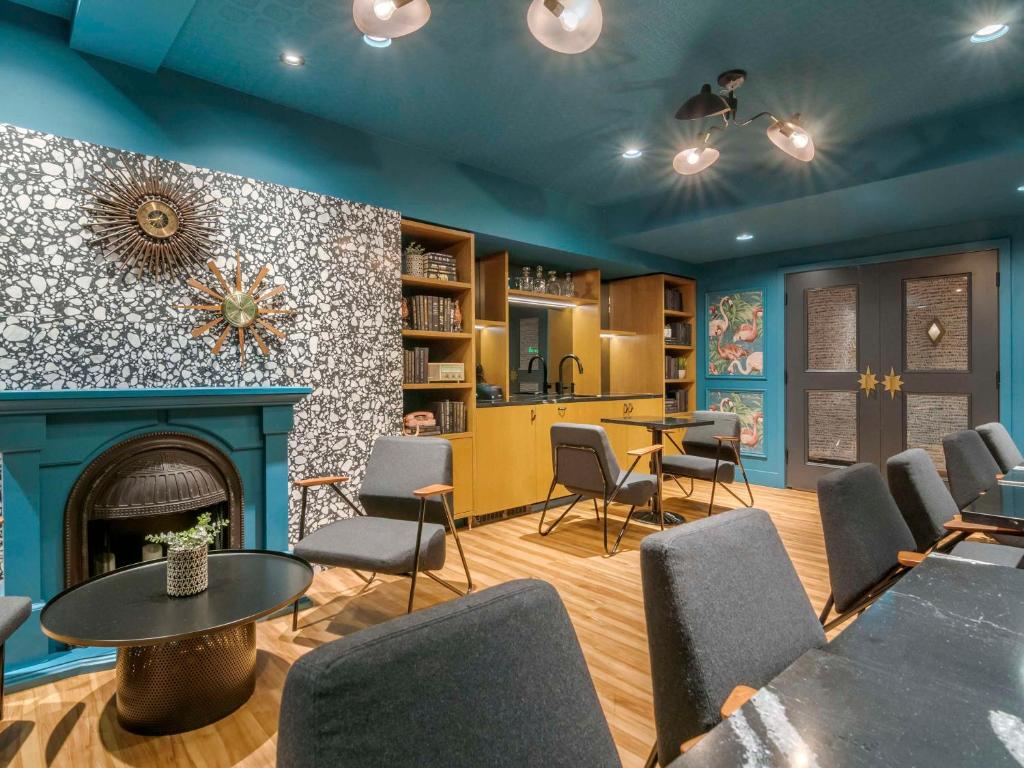 a room with a fireplace and tables and chairs at Hotel Belmont Vancouver - MGallery Collection in Vancouver
