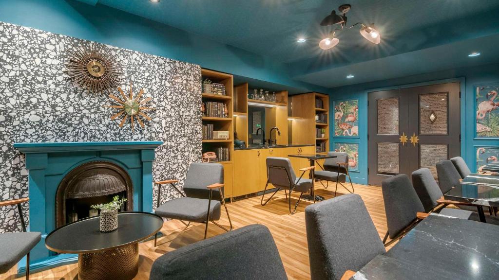 a room with a fireplace and tables and chairs at Hotel Belmont Vancouver - MGallery Collection in Vancouver