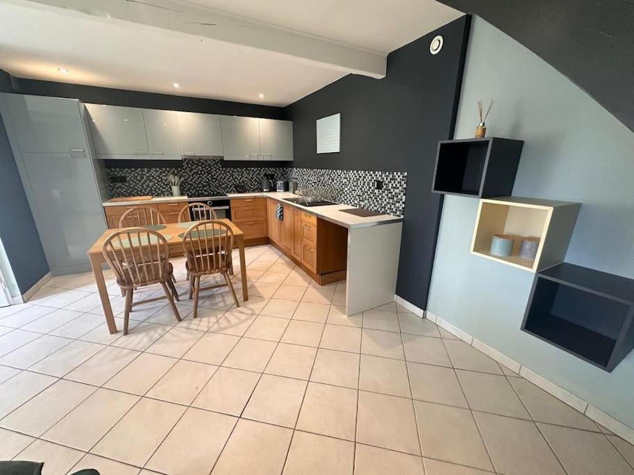 a large kitchen with a table and chairs in it at Petite maison de village 2 in Saint-Maurice-de-Rémens