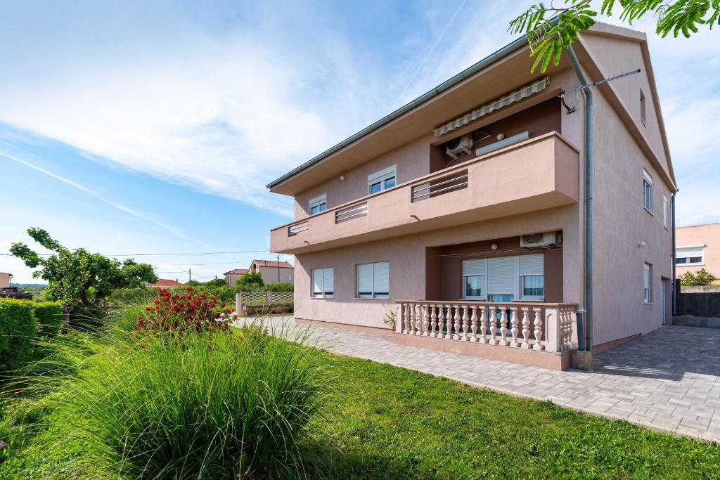 a large house with a balcony and grass at MY DALMATIA - Sea view apartment Nika with private parking in Posedarje