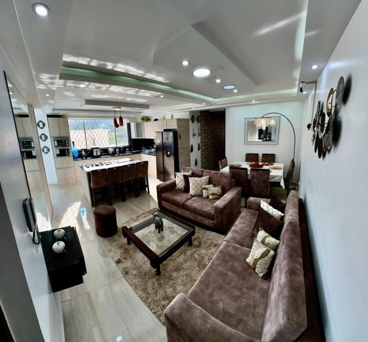 Una gran sala de estar con sofás y una mesa. en Apartamento de lujo, en Ibarra
