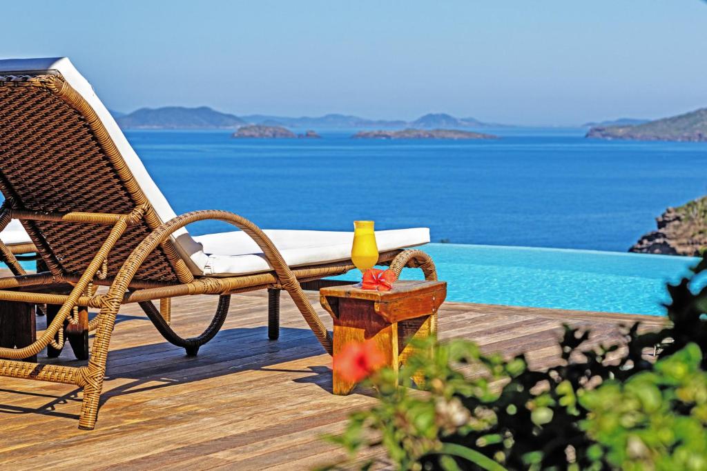 a wicker chair sitting on a deck next to a swimming pool at Gringos Boutique Hotel in Búzios