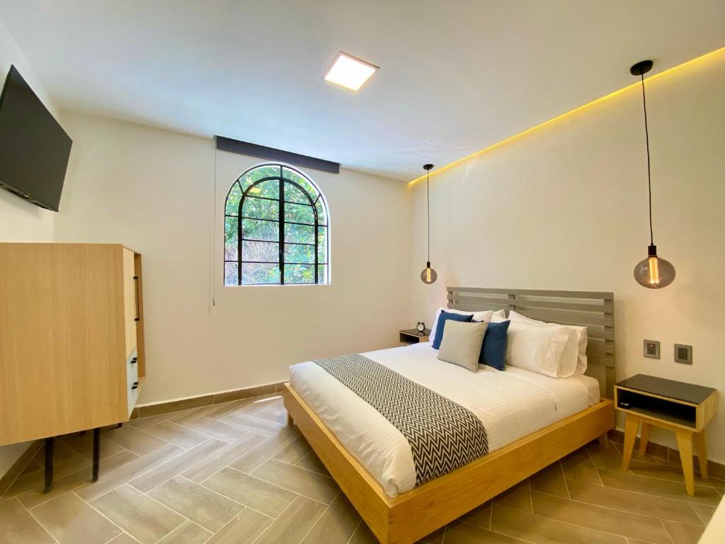 a bedroom with a bed with a tv and a window at Second Home Tamesis in Mexico City