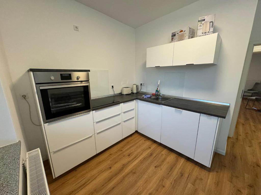 City-Krefeld Luxus 3 Zimmer Apartment mit Balkon في كريفيلد: مطبخ فيه دواليب بيضاء واجهزة سوداء