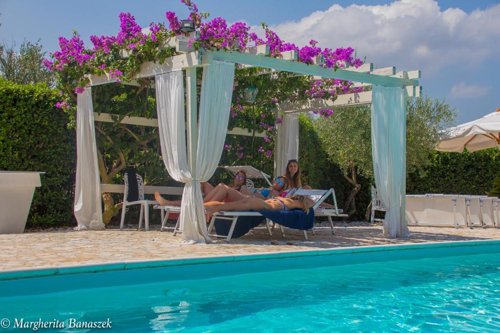 a group of people laying in chairs by a pool at Villa Floridia in Torrevecchia Teatina