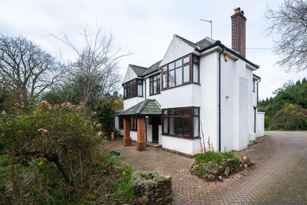 a white house with black windows and a brick driveway at Over Lane in Almondsbury