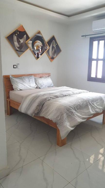 a bed in a bedroom with pictures on the wall at Les Résidences JMK in Abidjan