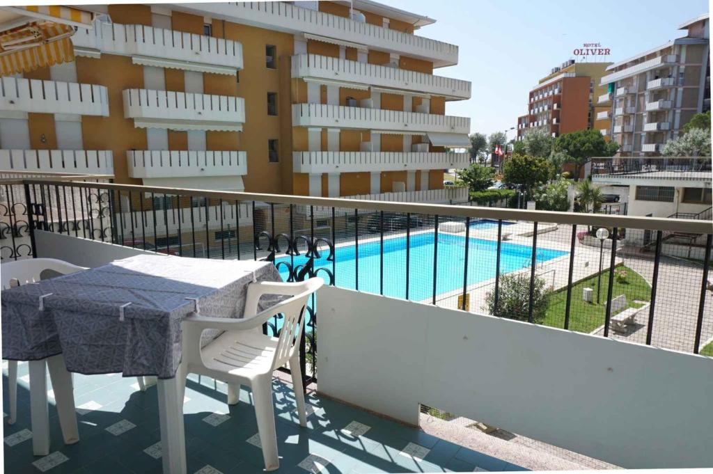 a balcony with a table and chairs and a swimming pool at Apartment in Porto Santa Margherita 48301 in Porto Santa Margherita di Caorle