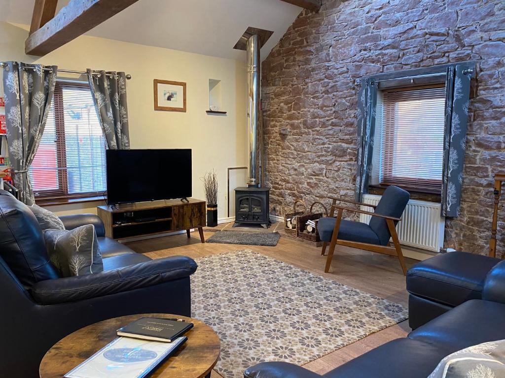 a living room with a tv and a brick wall at Stable Cottage in Wigton