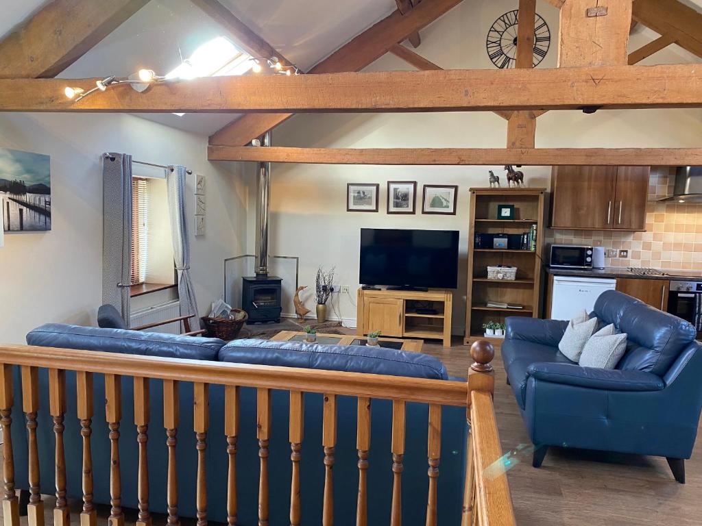 a living room with a blue couch and a tv at Hayloft Cottage in Wigton