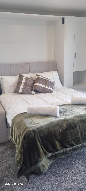 a large bed with white sheets and pillows on it at CBD Upstairs Studio Apartment in Christchurch