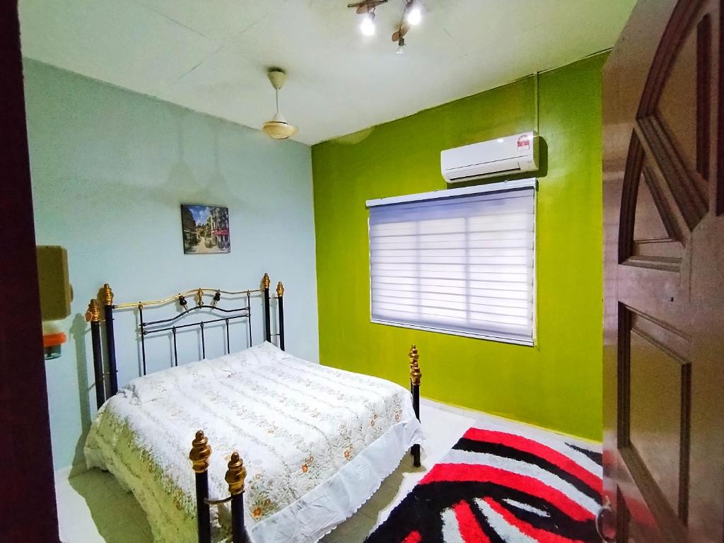 Temu 2U Villa في ميلاكا: غرفة نوم مع سرير وجدار أخضر