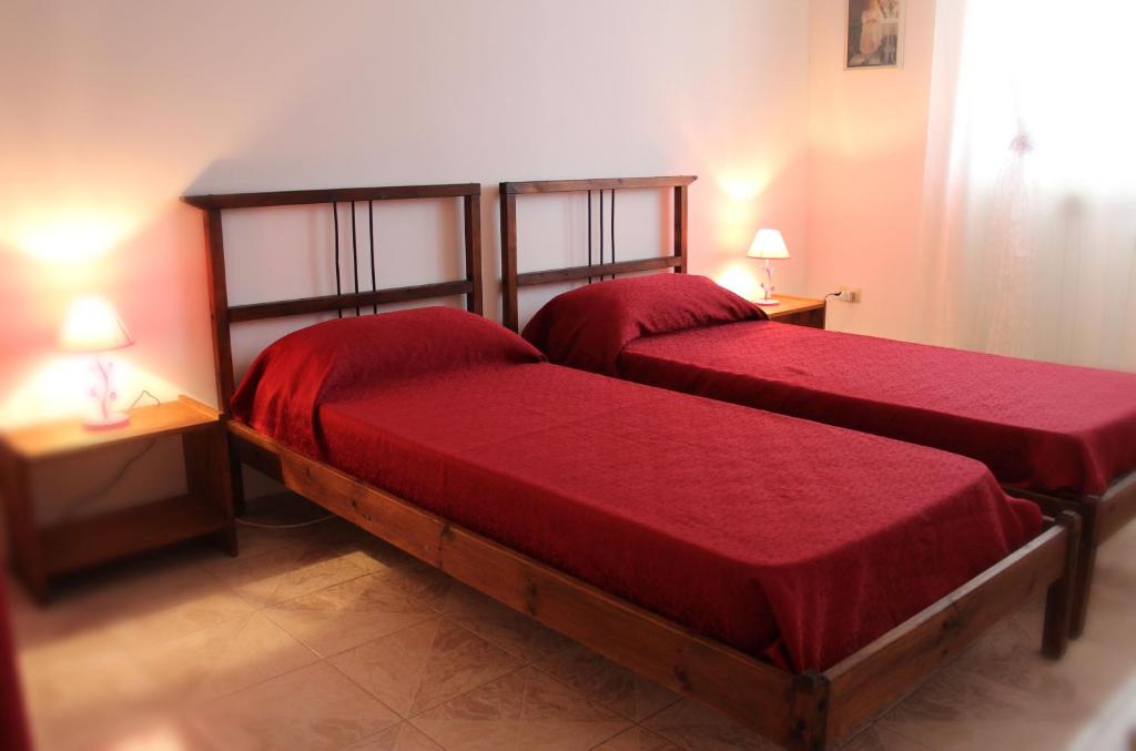 2 posti letto in una camera con lenzuola rosse e lampade di Stelle Sul Salento Holiday Home a Marina di Mancaversa