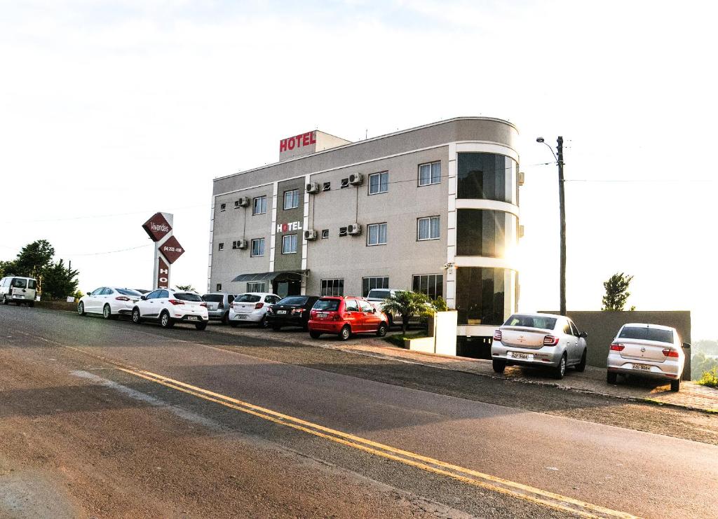 a parking lot with cars parked in front of a building at Vivendas Hotel in Erechim