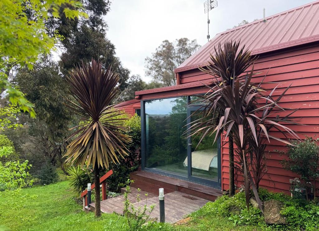 ein rotes Haus mit Glastüren an der Seite in der Unterkunft Red Gables Daylesford - Garden Suite & Hedge Suite in Daylesford