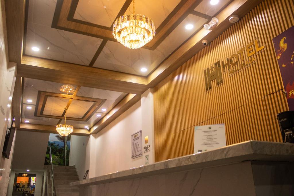a lobby with two chandeliers and a yellow wall at Hotel Mall plaza in Santa Marta