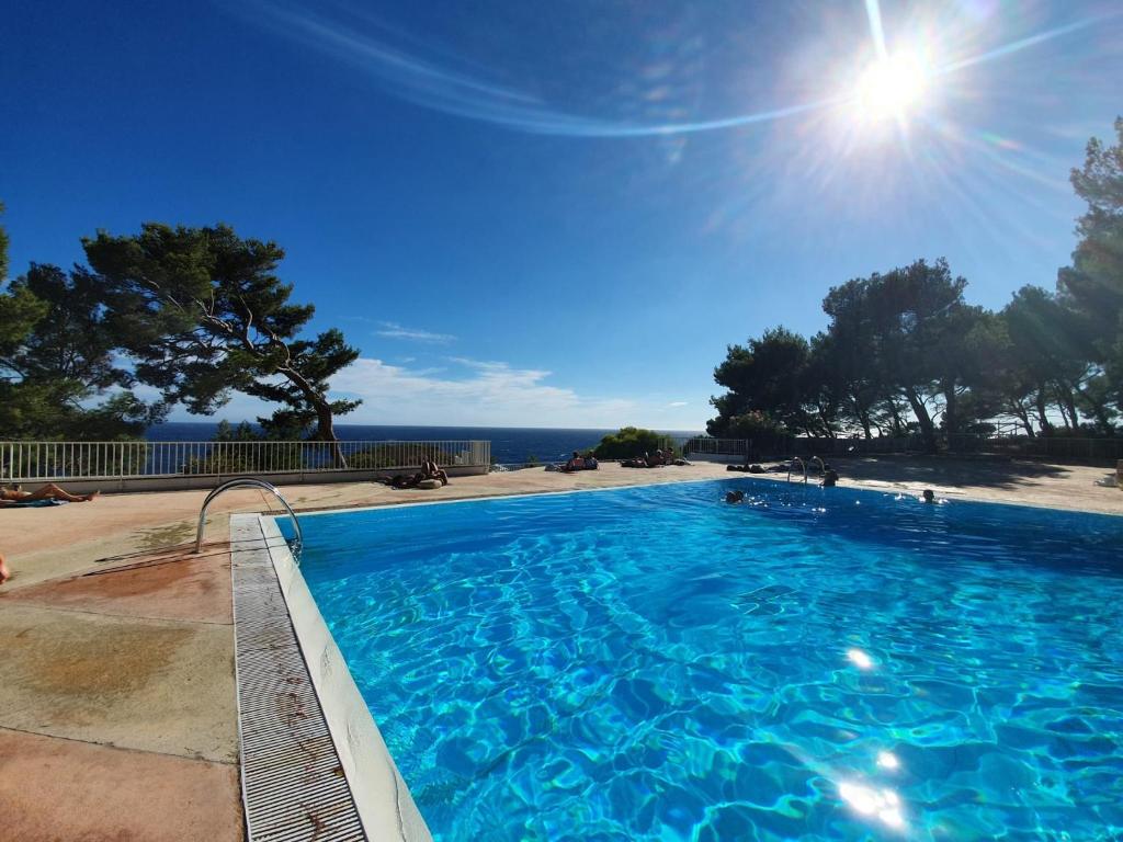 une grande piscine avec l'océan en arrière-plan dans l'établissement Studio les pieds dans l'eau dans résidence front de mer avec piscines, tennis, plage privée, à Bandol