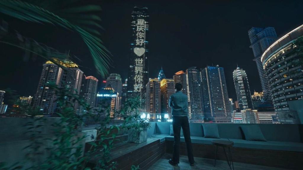a man standing on a rooftop looking at a city at night at Walling Hotel - Chongqing Jiefangbei Hongyadong in Chongqing