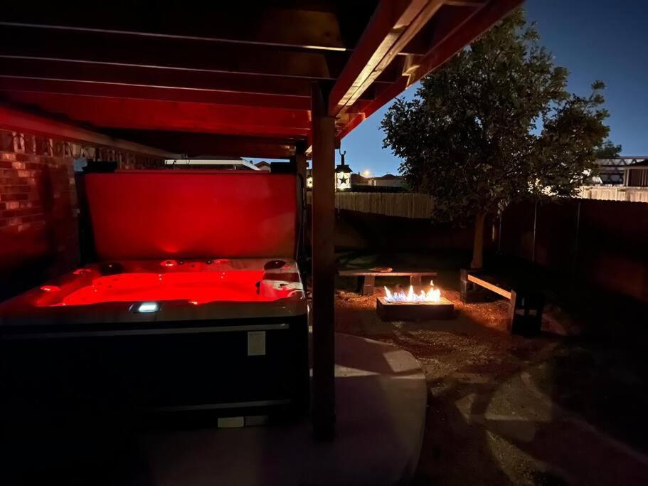 a red bed in a backyard with a fire pit at HotTub-King Bed -Fire pit-BBQ-Pristine Kitchen in Odessa