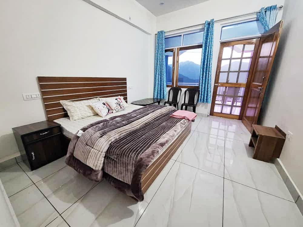 una camera da letto con un letto grande e una grande finestra di Chandarshila hike homestay a Ukhimath
