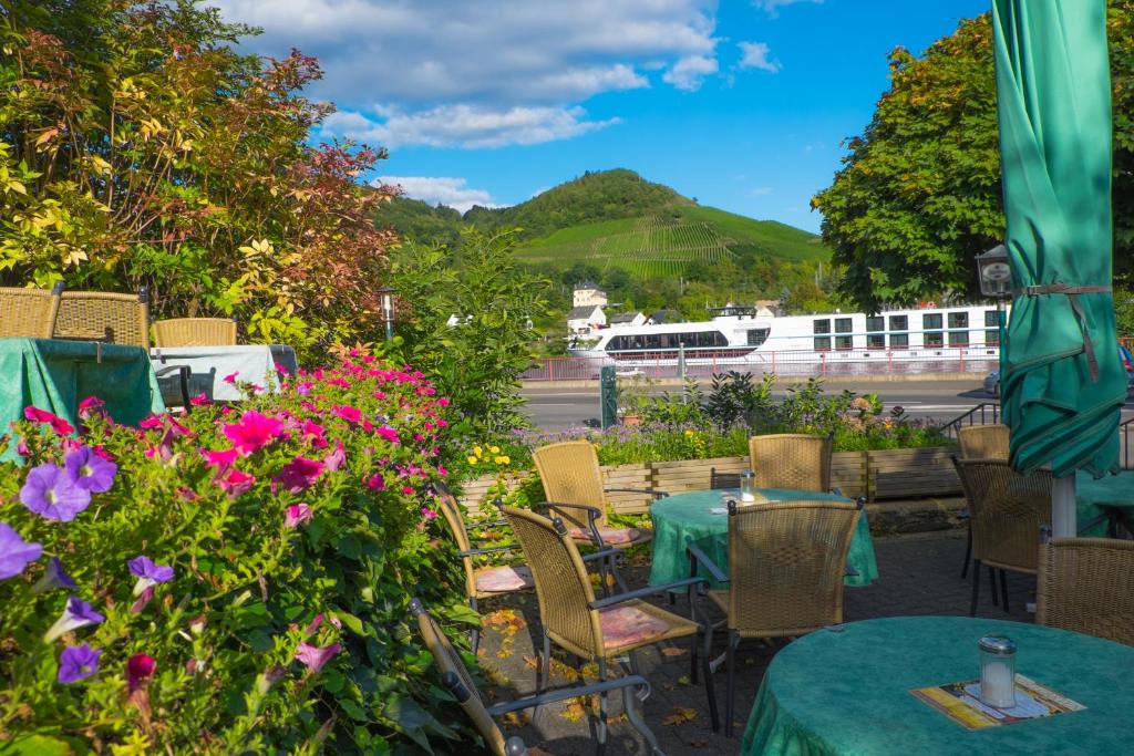 een tafel en stoelen met bloemen en een trein op de achtergrond bij Panorama-Café MOSELGARTEN in Alf