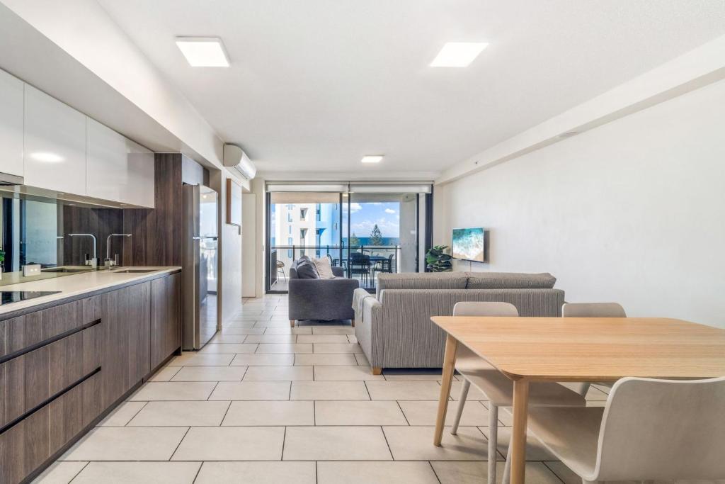 穆卢拉巴First Light Mooloolaba 9th floor apartment with ocean views的配有桌子和沙发的厨房和客厅