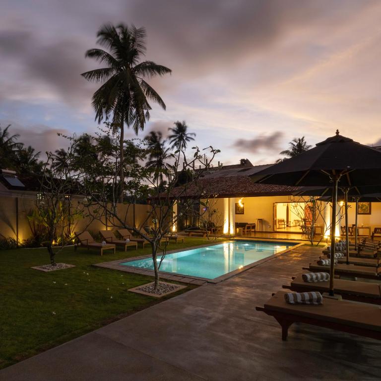 un resort con piscina di notte di Mudliyar House a Hikkaduwa