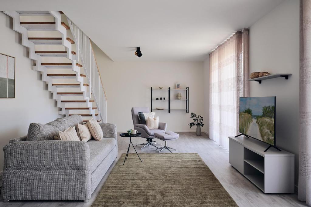 a living room with a couch and a staircase at Maisonette-Apartment A11 - zwei Schlafzimmer, zwei Bäder, zwei Balkone & zwei Terrassen im "Pine Hill Resort" in Zirchow