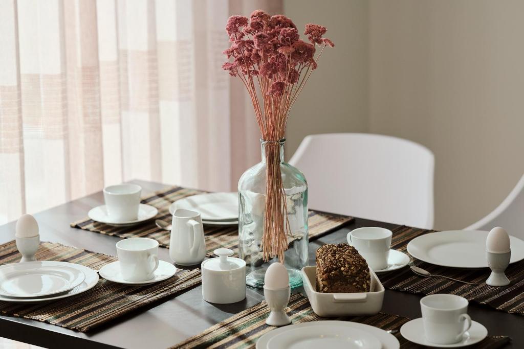 a table with plates and a vase with flowers in it at Apartment A6 - mit großem Bad & großem überdachtem Balkon, vom Wohn- und Schlafzimmer aus begehbar im "Pine Hill Resort" in Zirchow