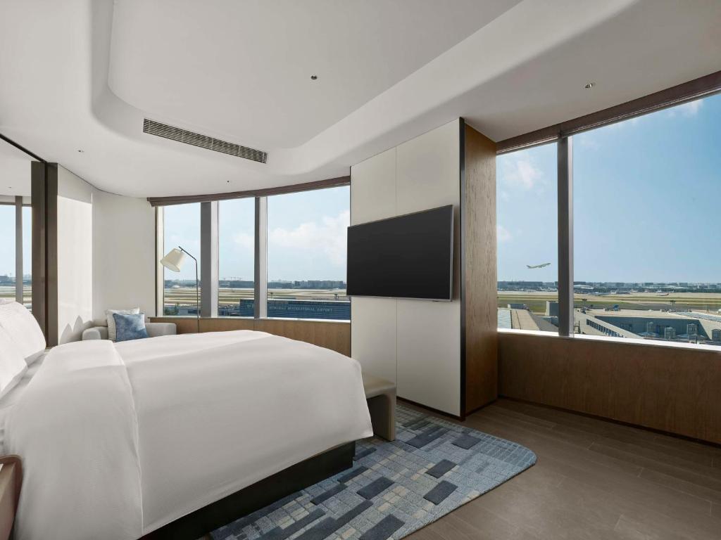 a bedroom with a large white bed and large windows at Hilton Shanghai Hongqiao International Airport in Shanghai
