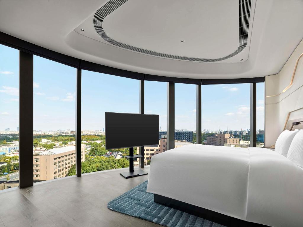 a bedroom with a white bed and a flat screen tv at Hilton Shanghai Hongqiao International Airport in Shanghai