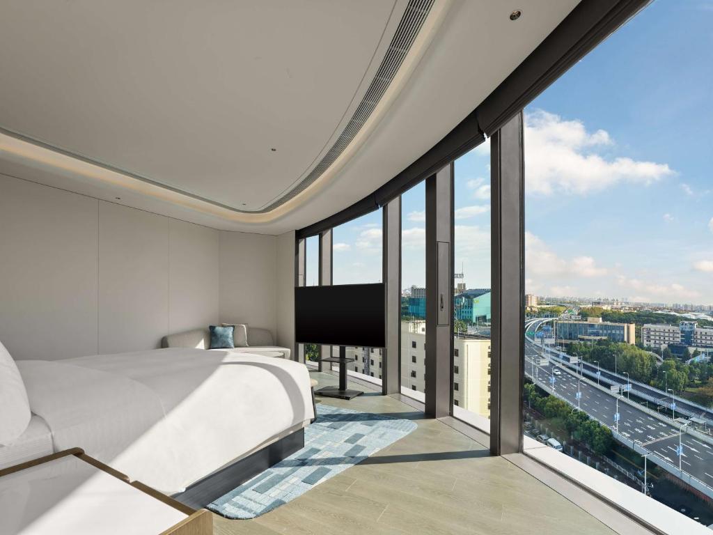 a bedroom with a bed and large glass windows at Hilton Shanghai Hongqiao International Airport in Shanghai