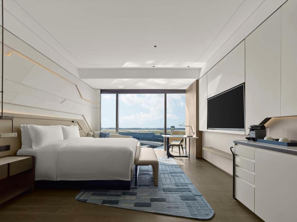 a hotel room with a bed and a flat screen tv at Hilton Shanghai Hongqiao International Airport in Shanghai