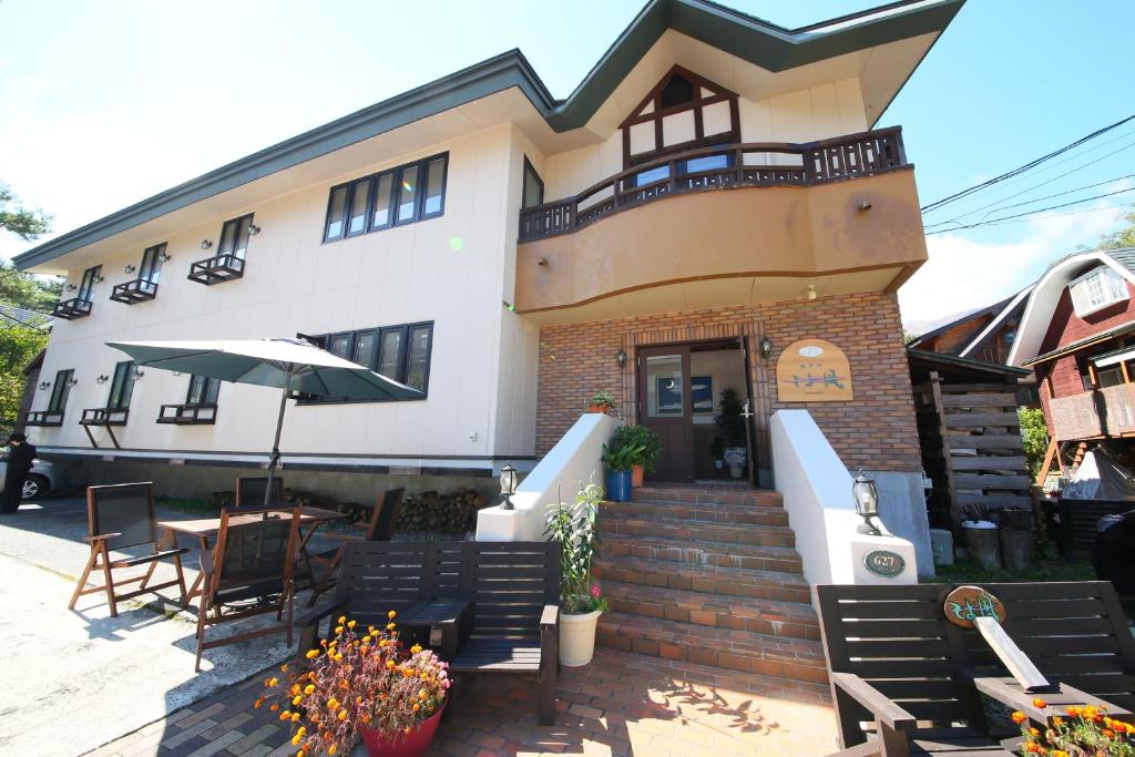 ein Gebäude mit einer Terrasse mit Stühlen und einem Sonnenschirm in der Unterkunft Hotel Soyokaze in Hakuba