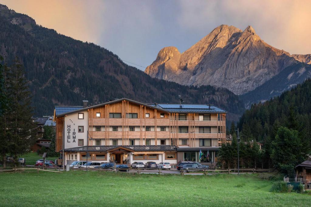 a large building with a mountain in the background at Dolomiten Hotel Irma in Canazei